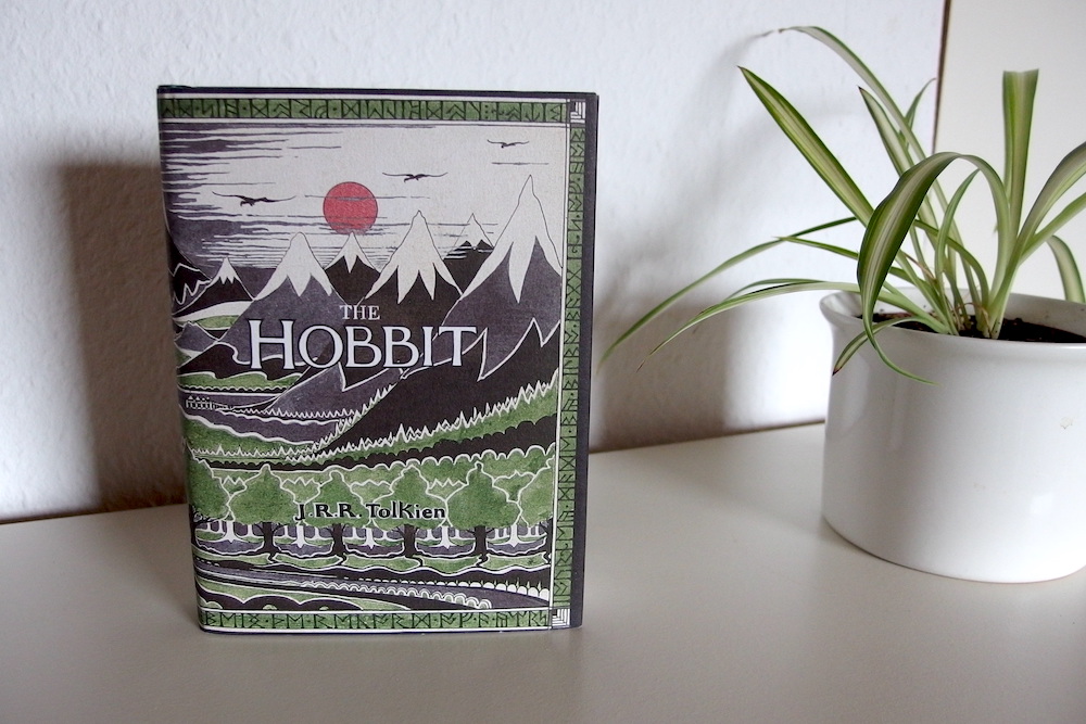 "Der Hobbit". Auf dem Cover ist eine Zeichnung von Bergen, Wald und einer roten Sonne zu sehen.