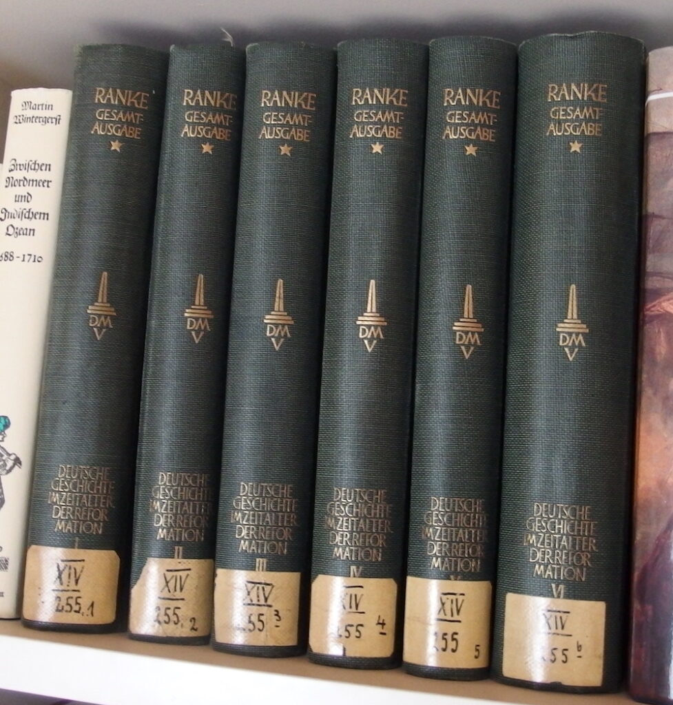 Sechs Bände "Deutsche Geschichte im Zeitalter der Reformation" im Regal, in grünes Leinen gebunden und mit Goldprägung.